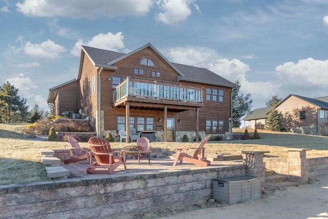 rear view of property with a balcony, an outdoor fire pit, and a patio area