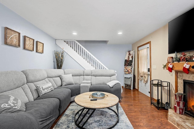 living room with a tile fireplace and dark hardwood / wood-style flooring