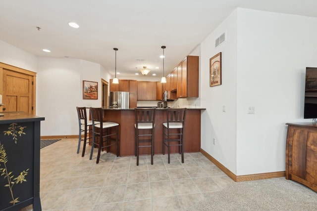 kitchen with hanging light fixtures, kitchen peninsula, appliances with stainless steel finishes, and a kitchen bar