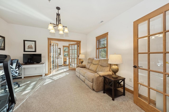 carpeted living room with a notable chandelier and french doors