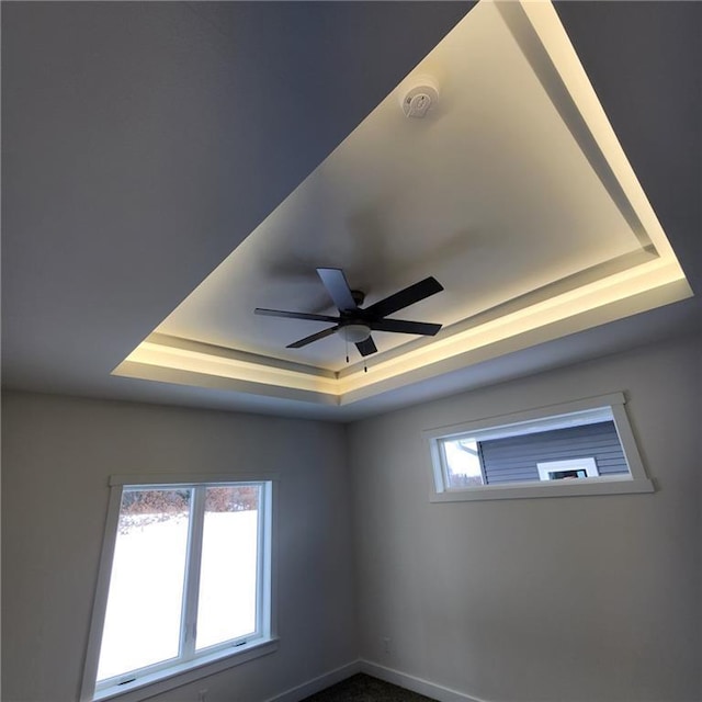 interior details featuring ceiling fan and a raised ceiling