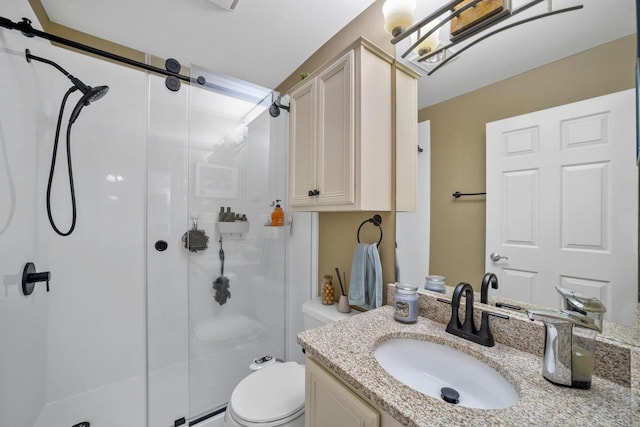 bathroom with vanity, a shower with door, and toilet