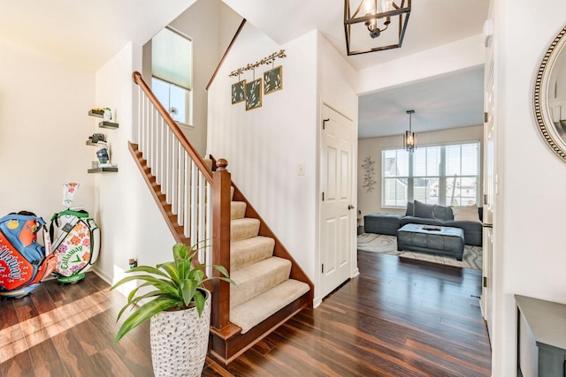 stairs featuring hardwood / wood-style flooring and an inviting chandelier