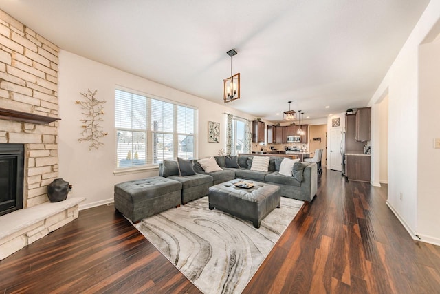 living room featuring dark hardwood / wood-style floors and a stone fireplace