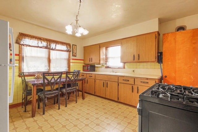 kitchen with decorative light fixtures, sink, a notable chandelier, and black gas range