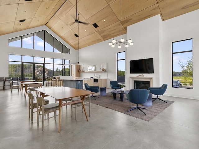 dining space with concrete floors, ceiling fan with notable chandelier, a high ceiling, and wood ceiling