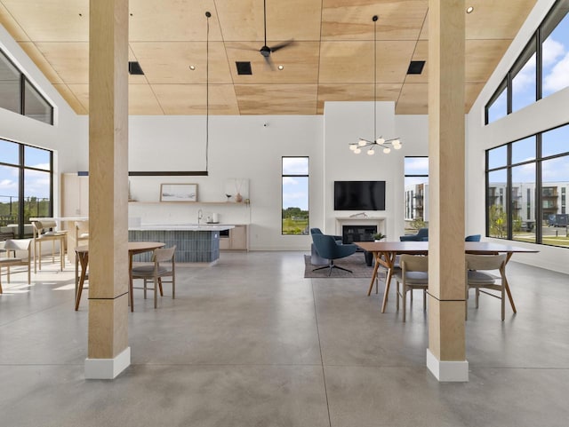 dining space with a towering ceiling, concrete flooring, and a notable chandelier