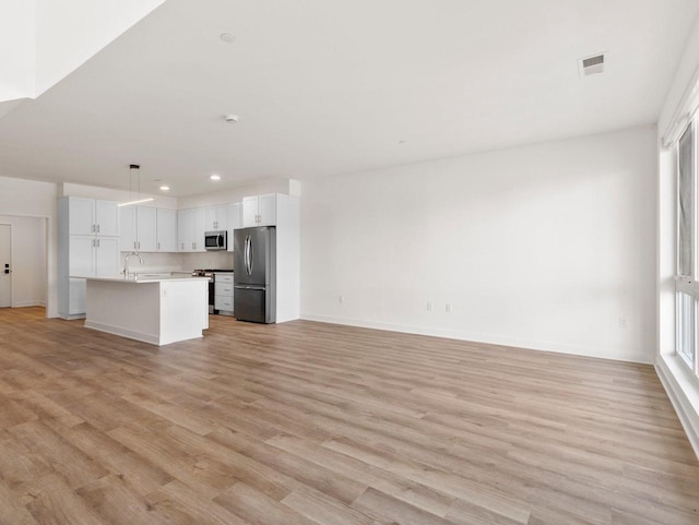 unfurnished living room with sink and light hardwood / wood-style floors