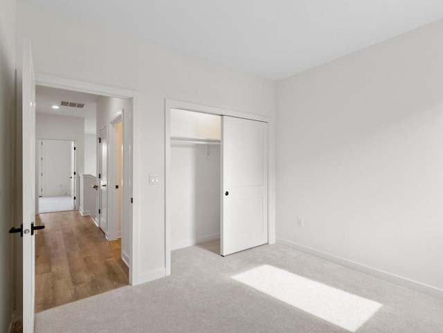 unfurnished bedroom featuring a closet and light carpet