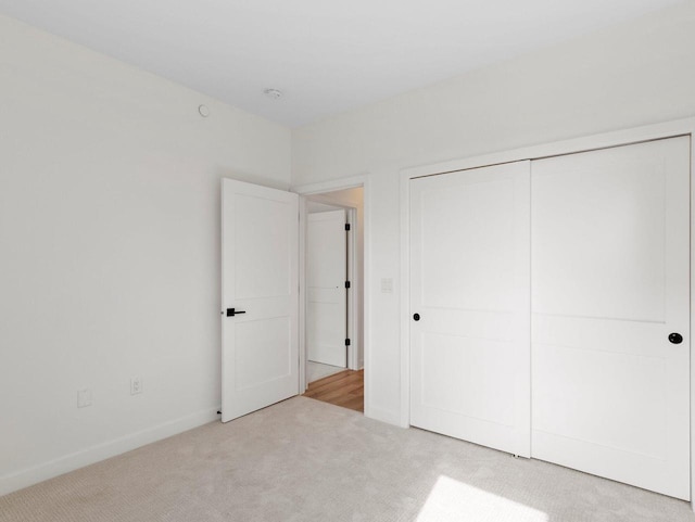 unfurnished bedroom with light colored carpet and a closet