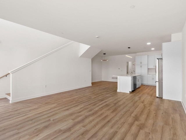 unfurnished living room featuring sink and light hardwood / wood-style flooring