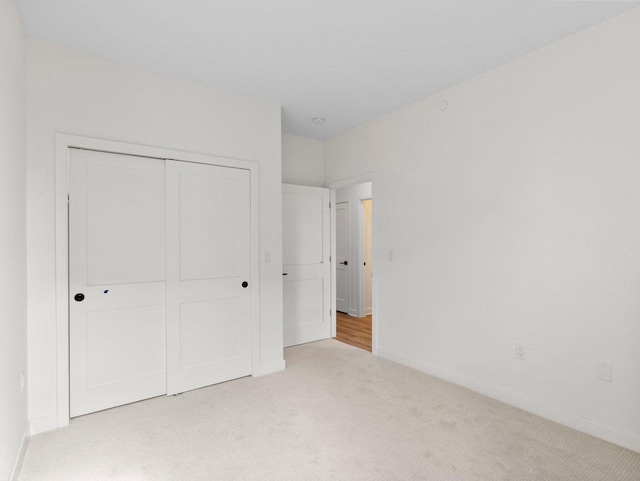 unfurnished bedroom featuring light carpet and a closet