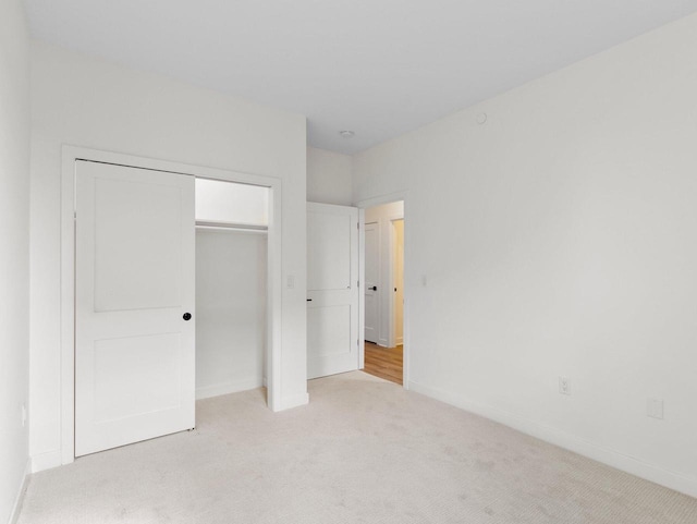 unfurnished bedroom with light colored carpet and a closet