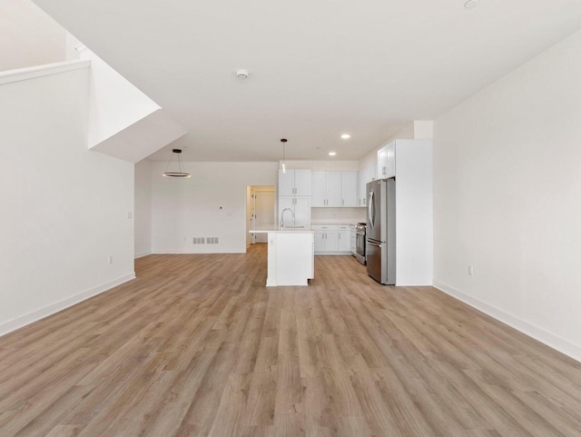 unfurnished living room with sink and light hardwood / wood-style floors