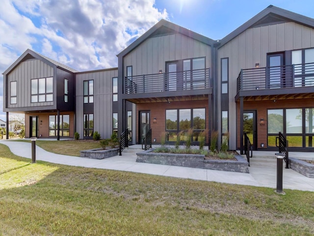 rear view of house featuring a balcony and a yard