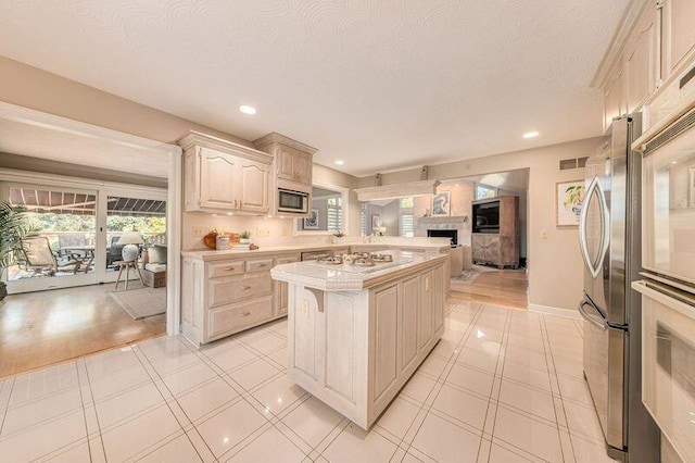 kitchen with white gas stovetop, a kitchen island, stainless steel microwave, and a textured ceiling