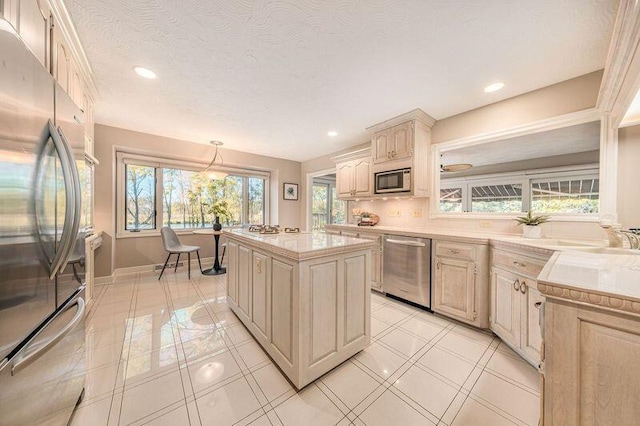 kitchen with a center island, appliances with stainless steel finishes, a textured ceiling, sink, and decorative light fixtures