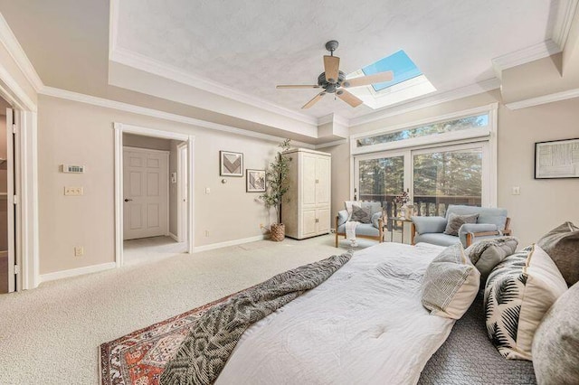 carpeted bedroom featuring ceiling fan, a tray ceiling, ornamental molding, and a skylight