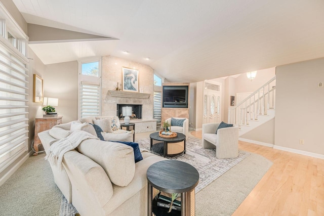 living room with light wood-type flooring, vaulted ceiling, and a large fireplace