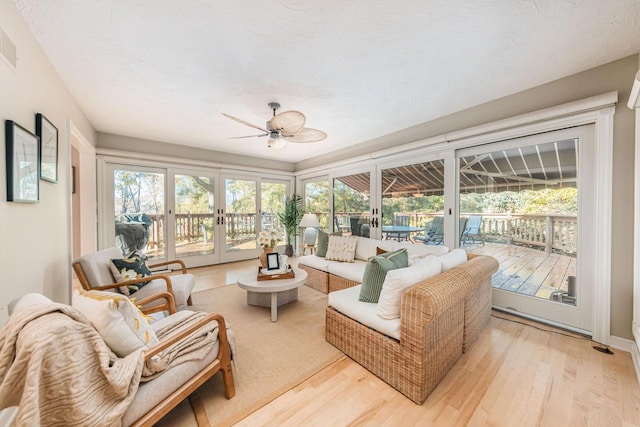 sunroom / solarium featuring ceiling fan and french doors