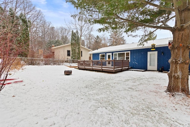 snow covered property featuring an outdoor fire pit and a wooden deck