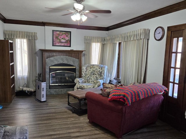 living room with ceiling fan, wood-type flooring, a tile fireplace, and crown molding