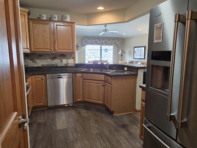 kitchen with ceiling fan, appliances with stainless steel finishes, sink, dark wood-type flooring, and tasteful backsplash