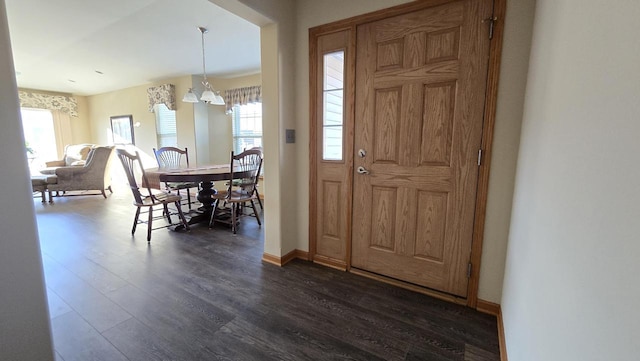 entrance foyer with plenty of natural light, dark wood-type flooring, and an inviting chandelier