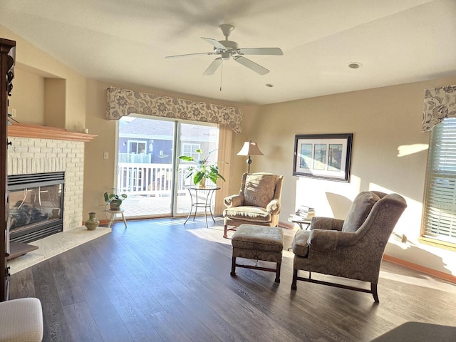 sitting room with a fireplace, wood-type flooring, and ceiling fan