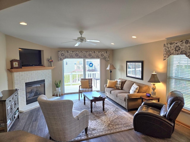 living room featuring a brick fireplace, dark hardwood / wood-style flooring, and ceiling fan