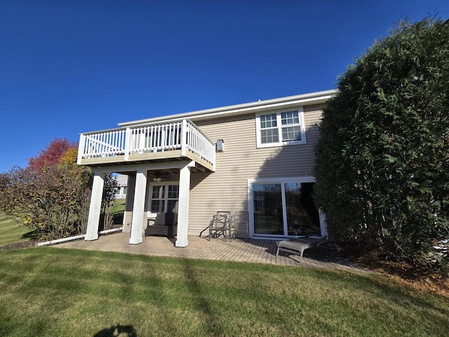 rear view of property featuring a deck, a patio area, and a lawn