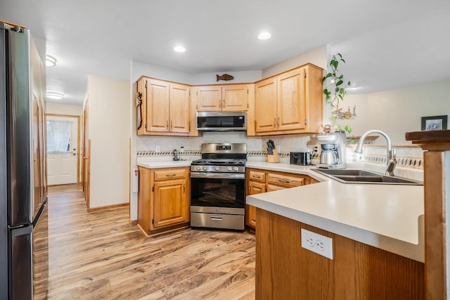 kitchen featuring kitchen peninsula, light brown cabinets, light hardwood / wood-style flooring, appliances with stainless steel finishes, and sink