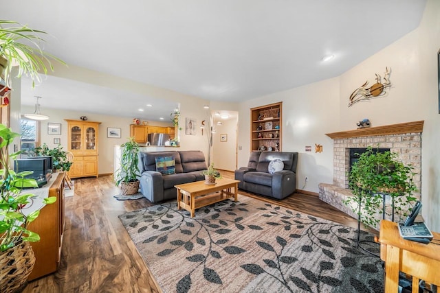 living room featuring built in shelves, a fireplace, and hardwood / wood-style flooring