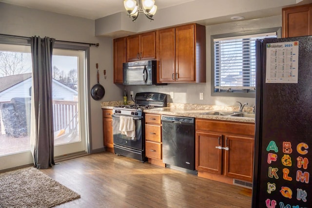 kitchen with a notable chandelier, sink, light hardwood / wood-style flooring, and black appliances