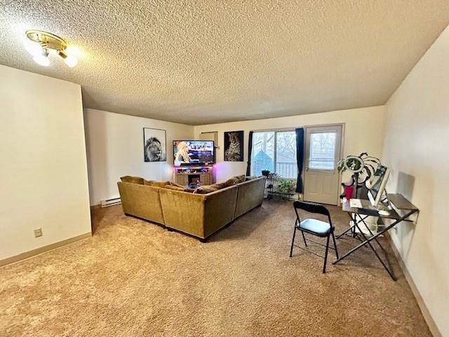 carpeted living room featuring a baseboard radiator and a textured ceiling