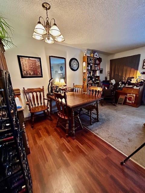 dining room with hardwood / wood-style flooring, a textured ceiling, and a notable chandelier