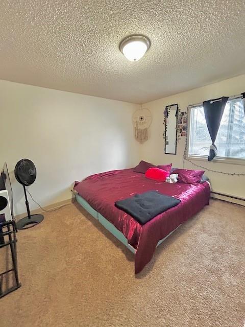 bedroom with carpet flooring, a textured ceiling, and a baseboard heating unit