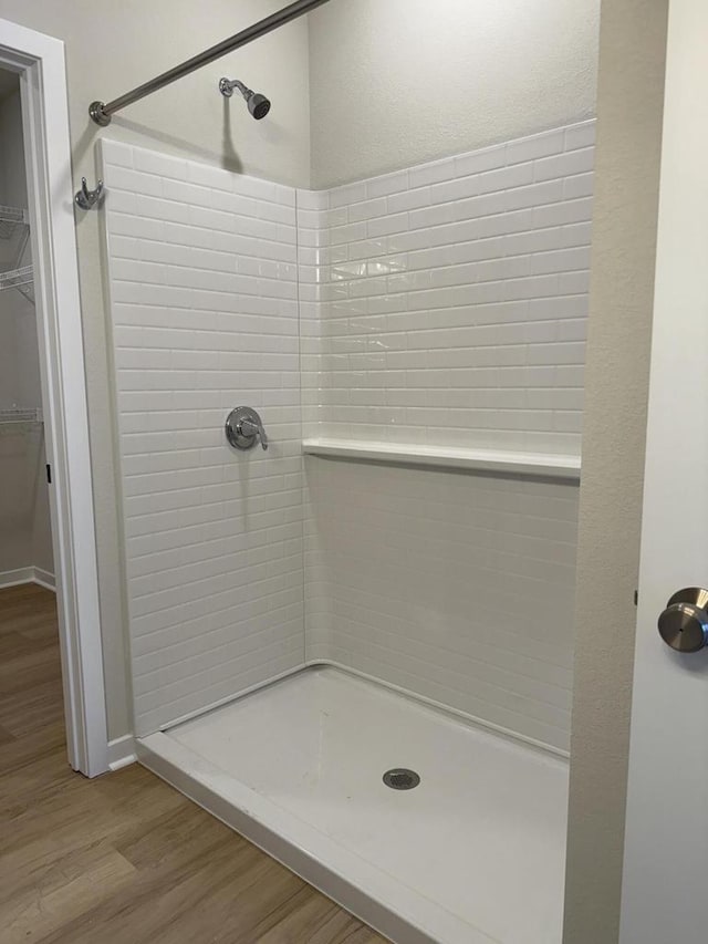 bathroom with hardwood / wood-style floors and a tile shower