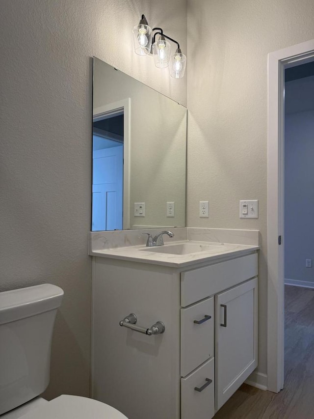 bathroom featuring hardwood / wood-style flooring, toilet, and vanity