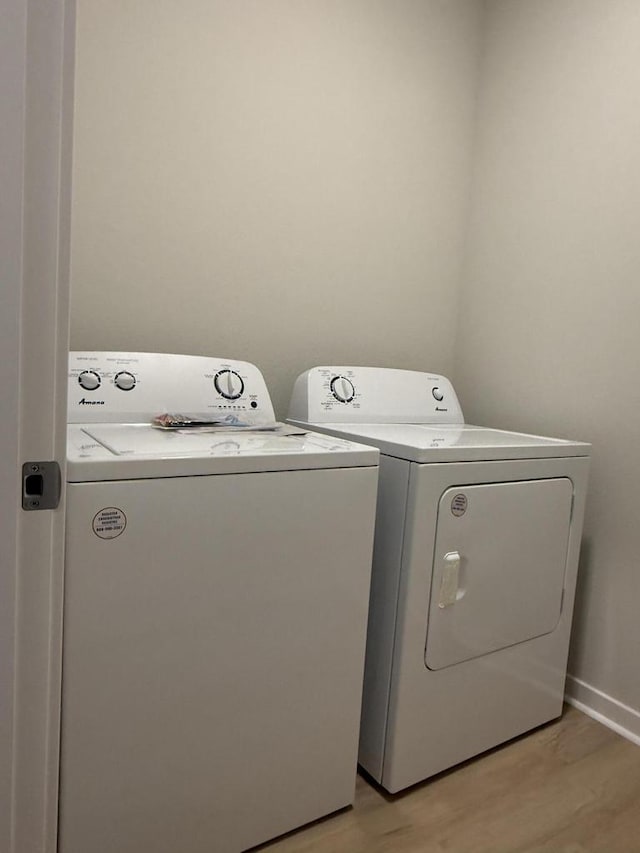 clothes washing area with light hardwood / wood-style flooring and washer and dryer