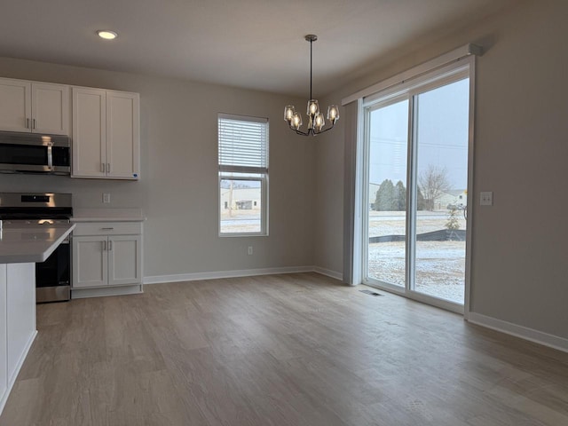 kitchen featuring stove, white cabinets, decorative light fixtures, and plenty of natural light