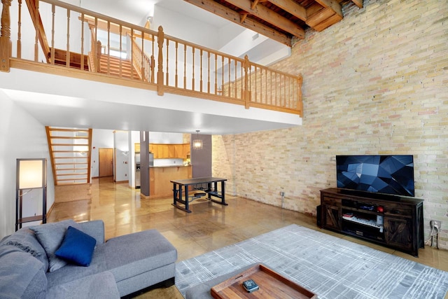 living room with brick wall, beam ceiling, and a towering ceiling