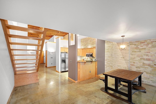 kitchen with stainless steel appliances, hanging light fixtures, and light brown cabinets