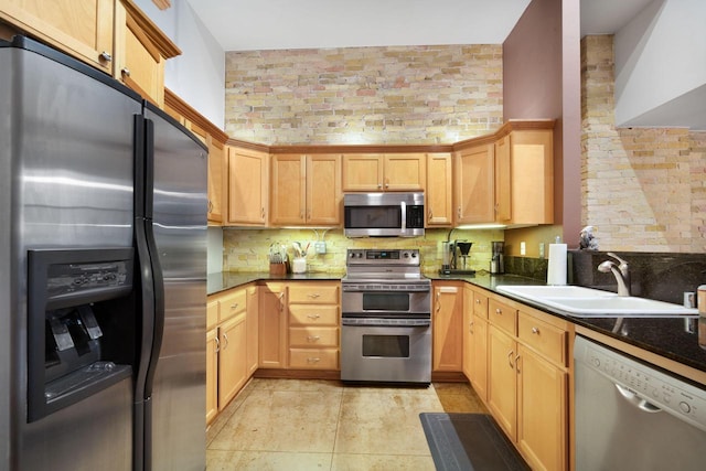 kitchen featuring brick wall, stainless steel appliances, light brown cabinetry, sink, and light tile patterned floors