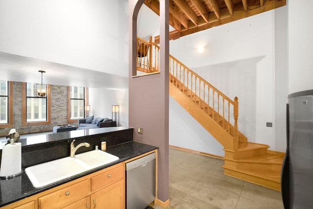 kitchen with appliances with stainless steel finishes, light brown cabinets, sink, hanging light fixtures, and a chandelier