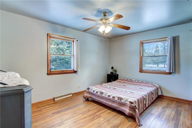 bedroom featuring wood-type flooring, baseboard heating, and ceiling fan