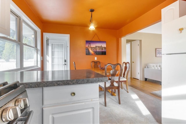 kitchen with white refrigerator, white cabinetry, gas range, and decorative light fixtures