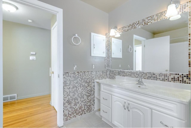 bathroom featuring hardwood / wood-style flooring, vanity, and tile walls