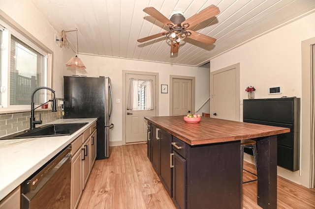 kitchen featuring pendant lighting, a kitchen island, black dishwasher, tasteful backsplash, and sink