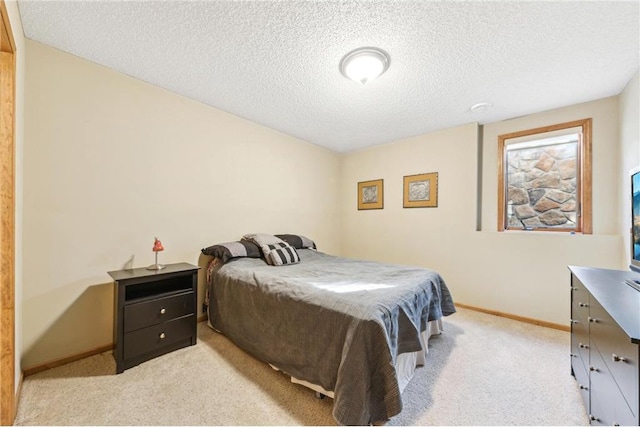 bedroom with light colored carpet and a textured ceiling